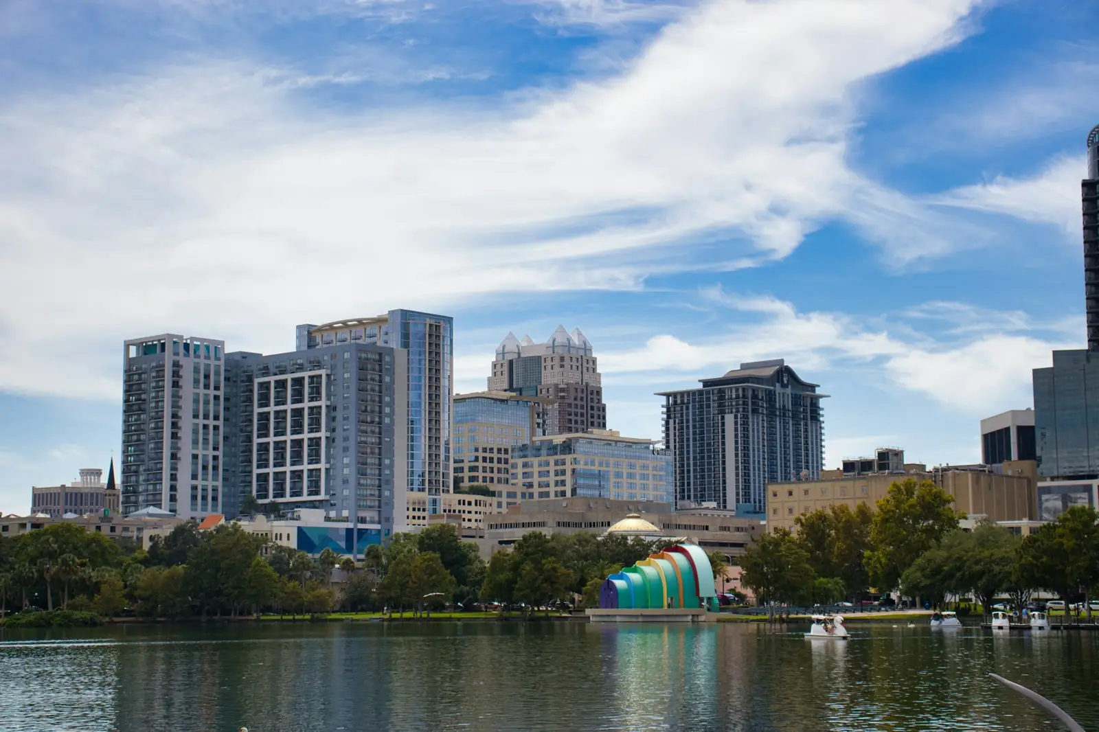 Downtown Orlando towers above Lake Eola under a blue sky with clouds