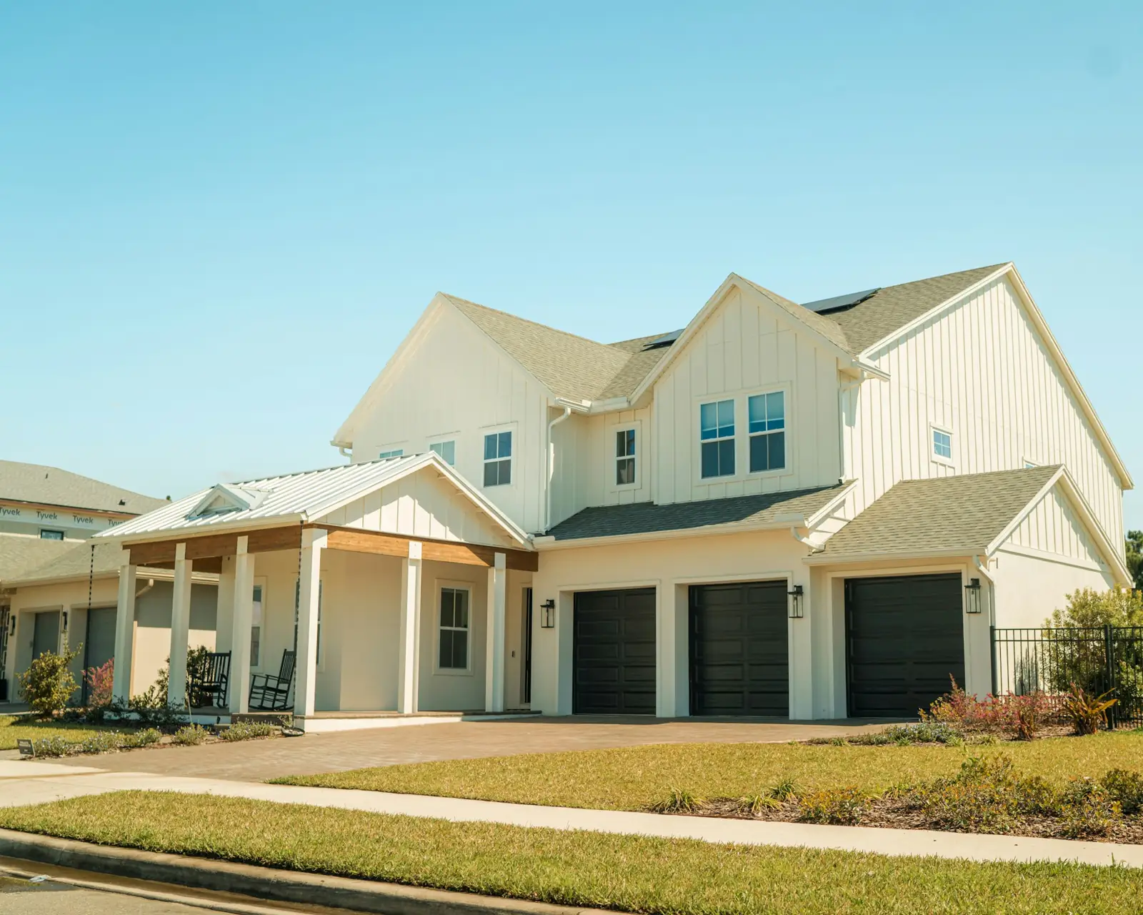 A two-story Florida house with three dark garage doors and a wide driveway