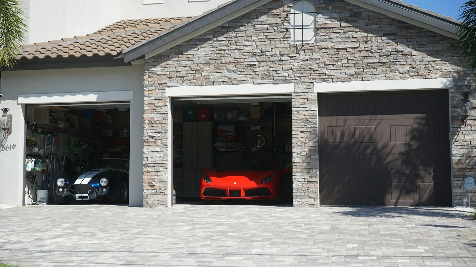 A stone-faced garage with three doors, two of them open